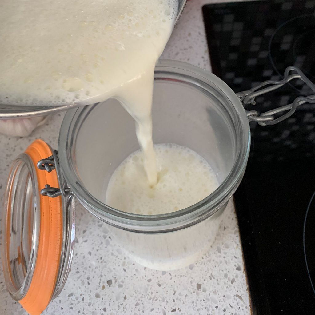 pouring milk into jar to make yoghurt